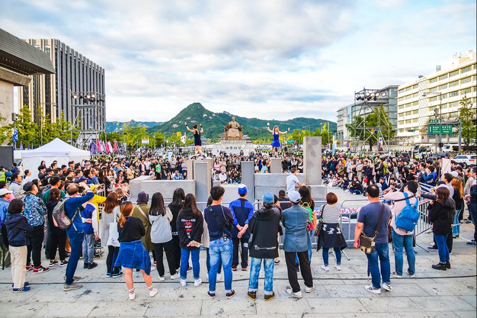 A group of people watch circus performers dance on grey blocks of different height