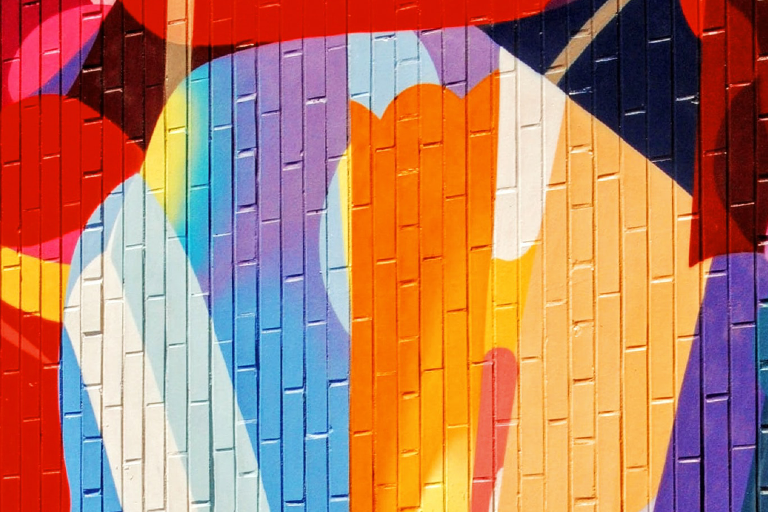 An image of visual art in various shapes and colours painted over a brick wall